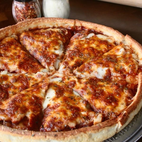 A deep-dish pizza from Baked, sliced into six pieces, with melted cheese and red sauce.