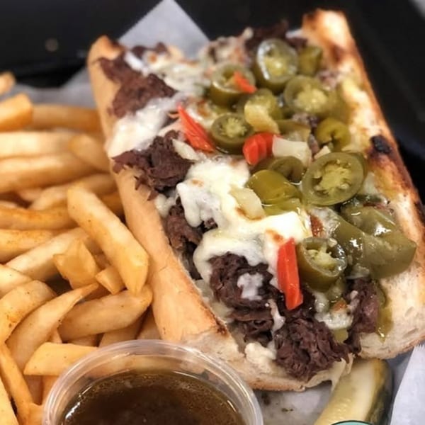 Baked's Italian beef sandwich with melted cheese, jalapeños, and red peppers, served with fries and au jus.