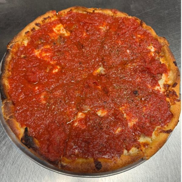 A Baked deep dish pizza, generously topped with bright red tomato sauce and herbs.